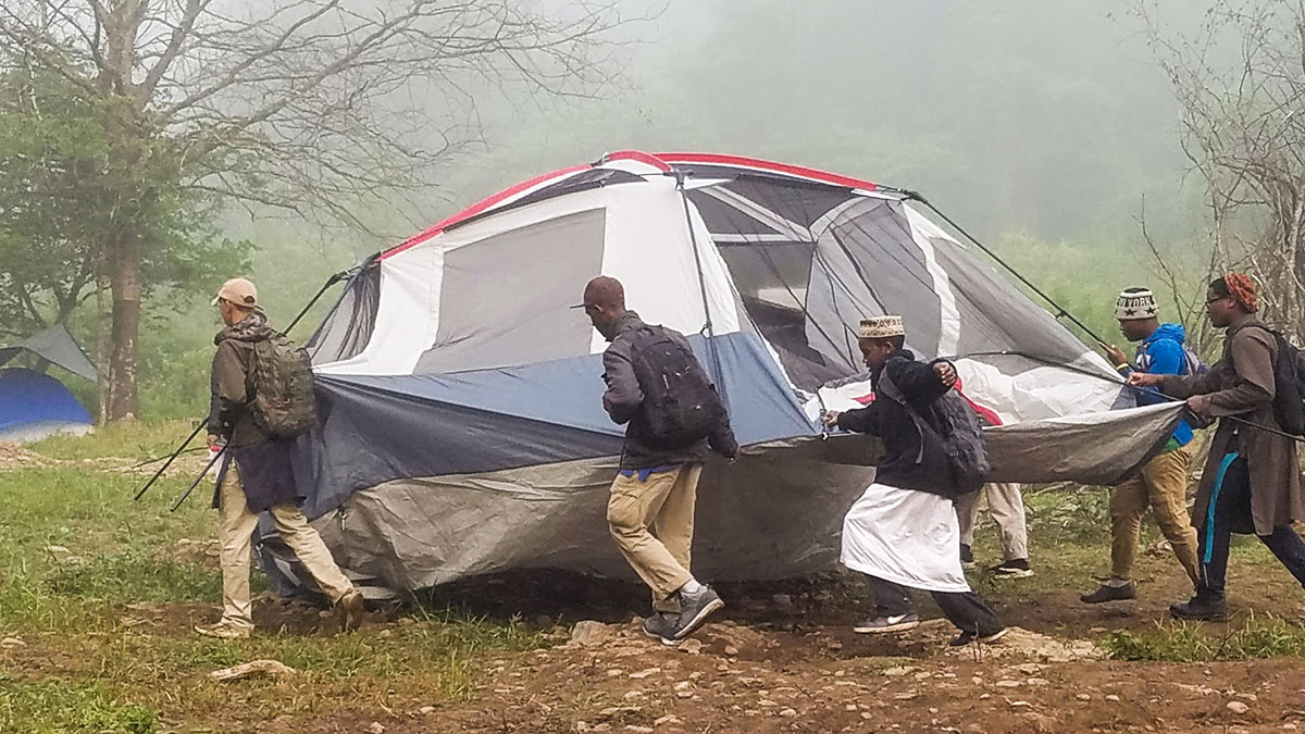 Scouts pitching a large tent in morning fog at camp