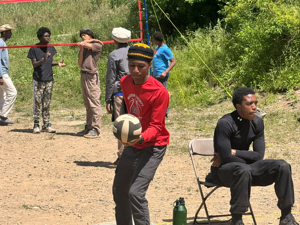 Scouts playing volleyball on an outdoor court at camp