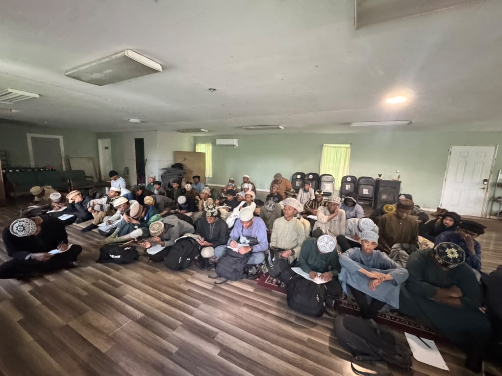 Scouts seated on the floor taking notes during an indoor Islamic studies class