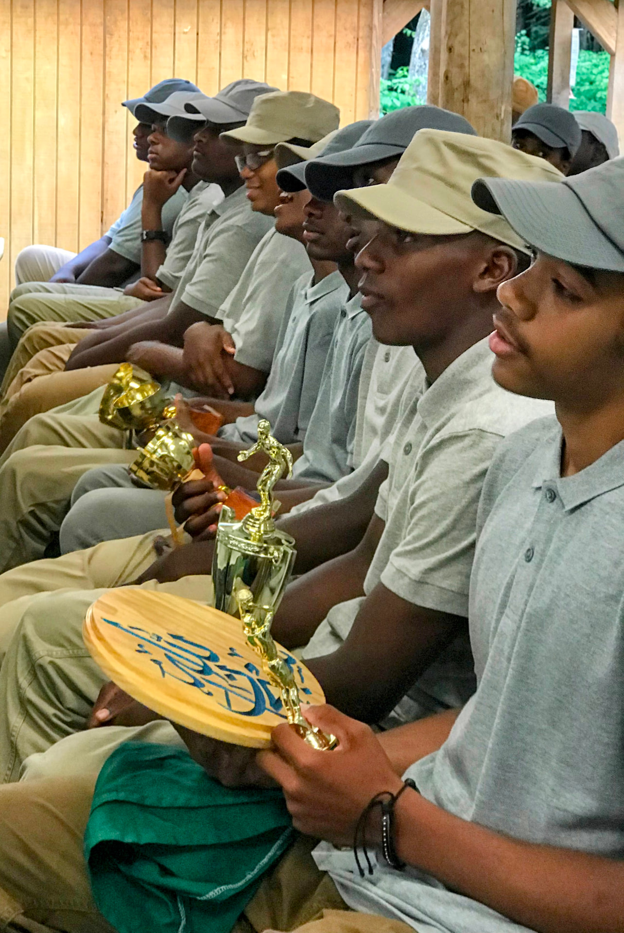 Scouts seated in a row holding trophies and engraved plaques