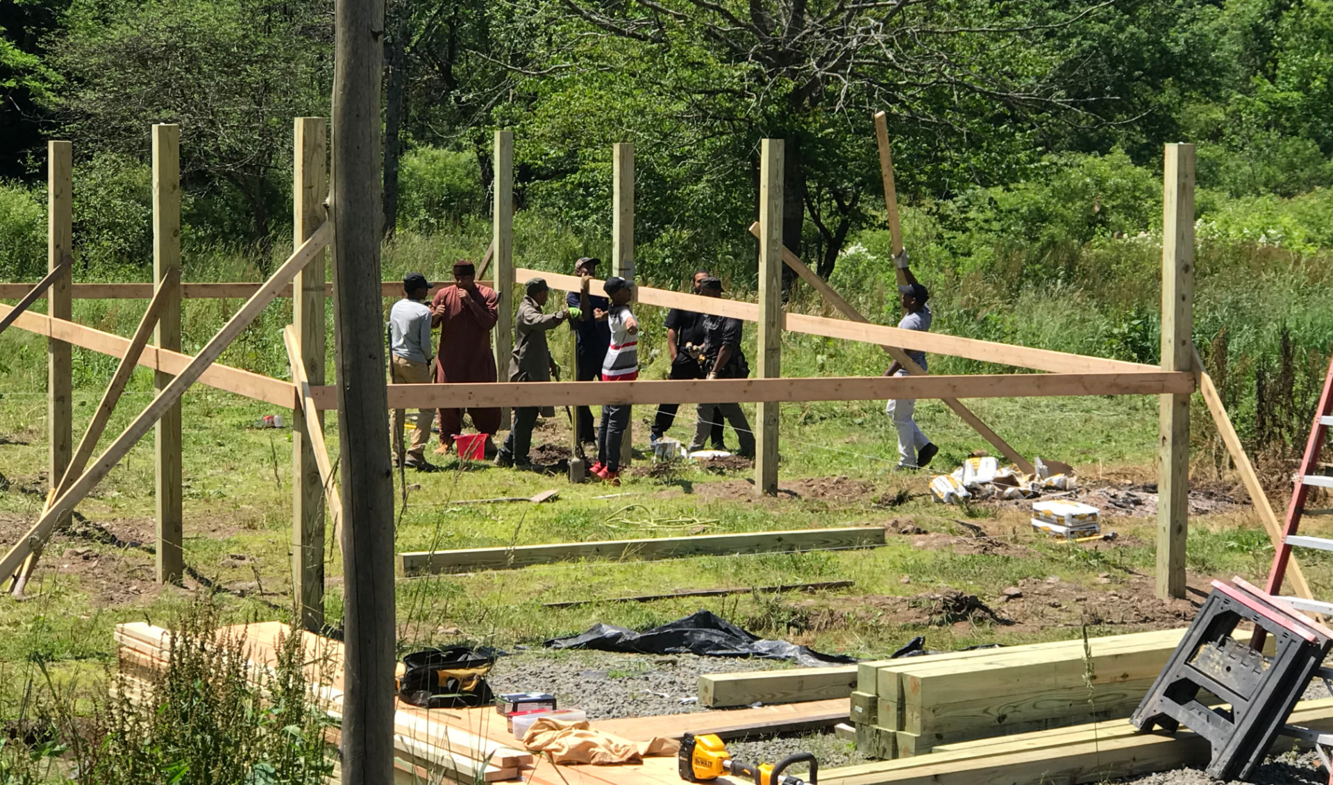 Scouts and instructors raising timber framing for a new camp structure