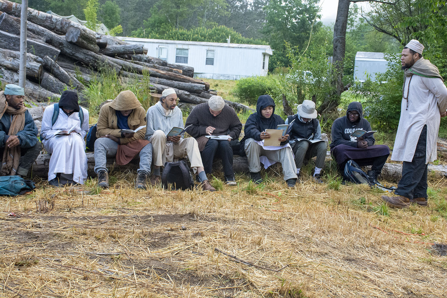 Scouts seated outdoors reading together while an instructor teaches